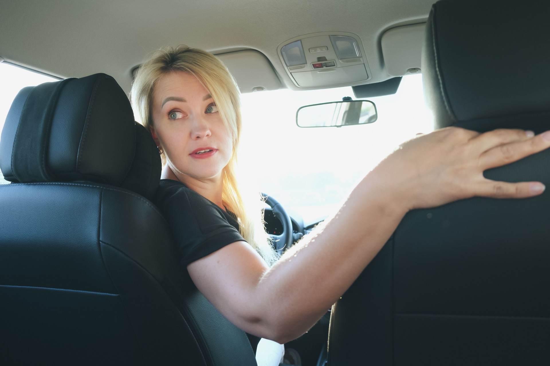 Attractive blonde woman driving a car turned around to look out the rear window