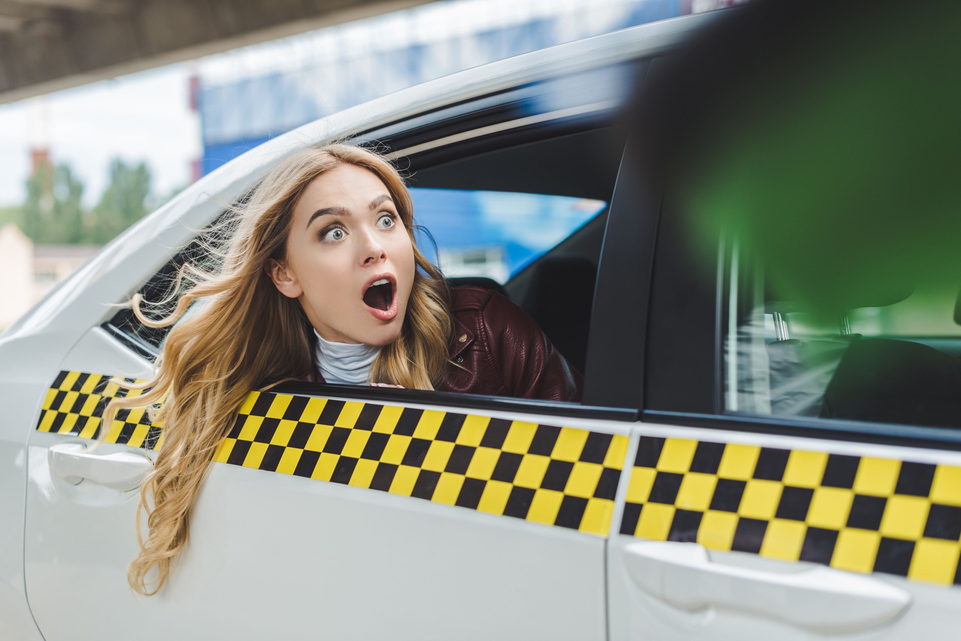 selective focus of shocked girl looking away through taxi window