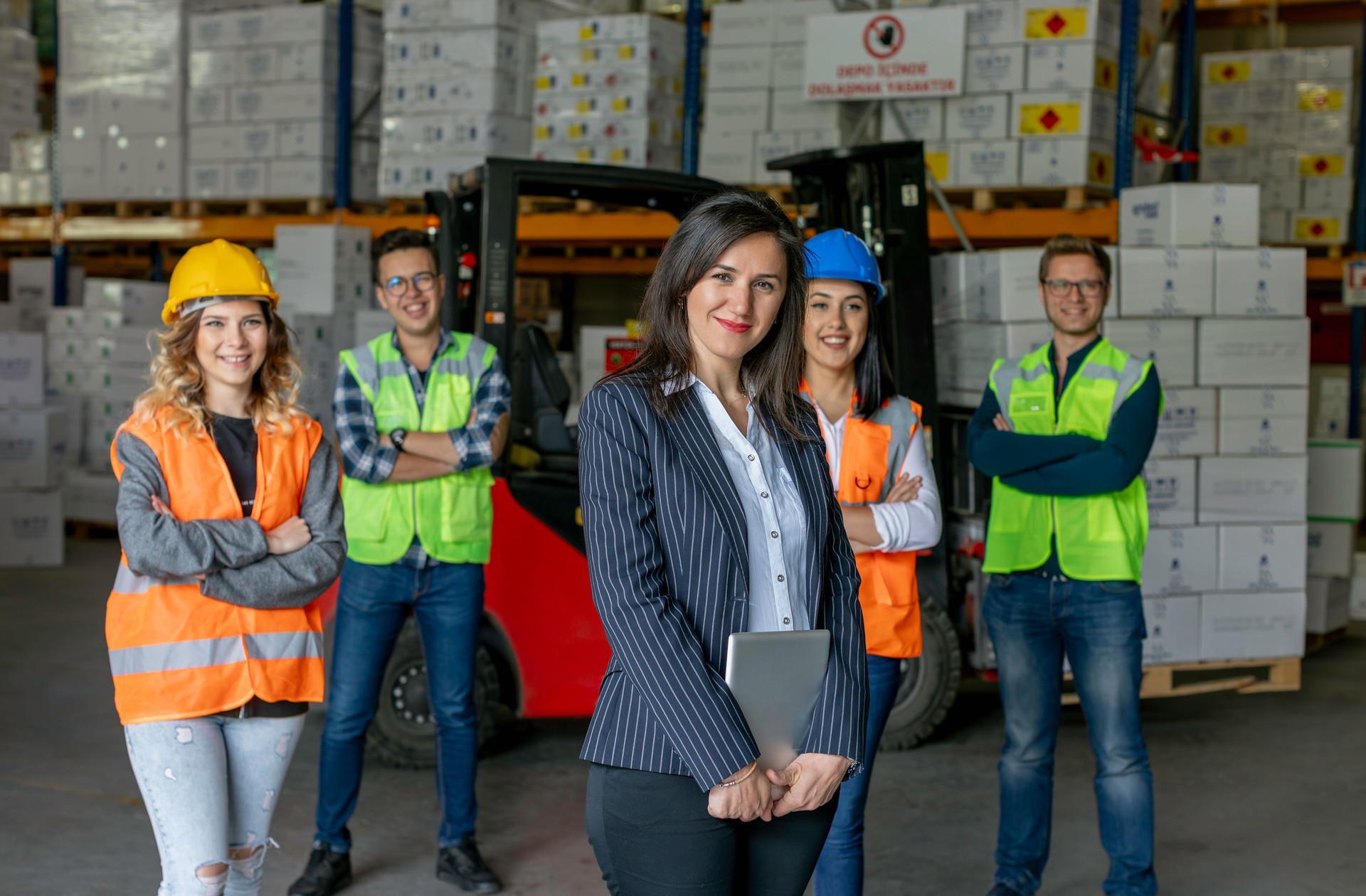 Portrait of female warehouse manager standing with diverse team in logistics facility.